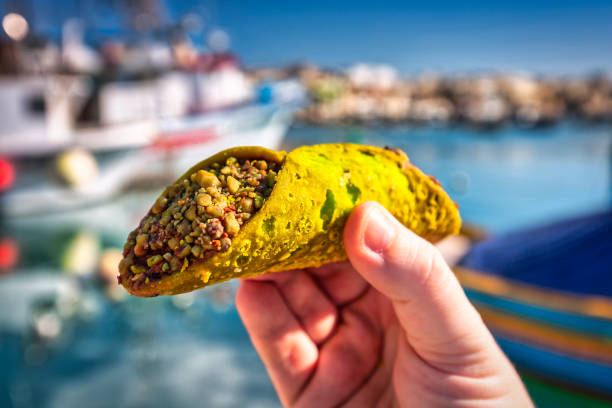 cannoli de pistacho maltés en la mano en el puerto pesquero - islas de malta fotografías e imágenes de stock