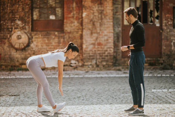 istock Young woman doing stretching exercise after jogging with her personal trainer 1311760472