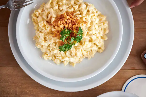 Homemade fresh cheese Spätzle Knöpfle with roasted onions is eaten by a young woman
