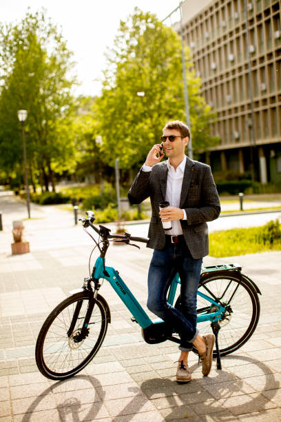 istock Young businessman using mobile phone by the ebike with takeaway coffee cup 1311763049