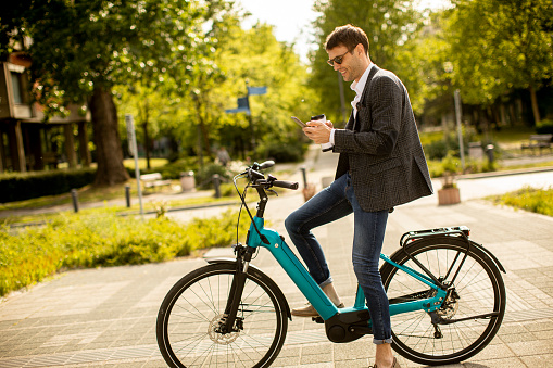 Handsome young businessman on the ebike with takeaway coffee cup