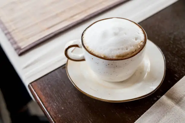 Top of view cappuccino coffee on wood table focus at white foam