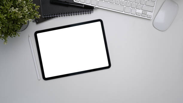 istock Top view og mock up digital tale with blank screen, stylus pen, keyboard and plant on white office desk. 1311763258