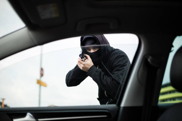 voleur pointant une arme à feu sur un conducteur - gun handgun violence kidnapping photos et images de collection