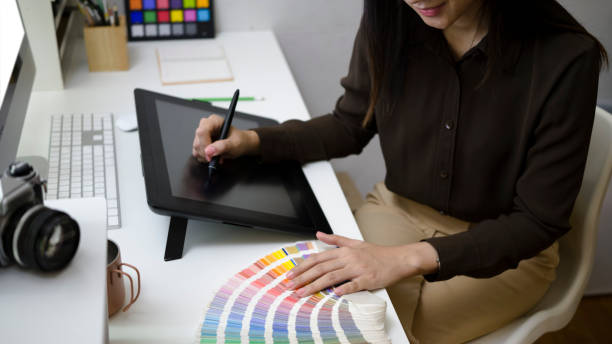 istock Smiling female graphic designer working with graphic tablet and color swatch samples at creative workplace. 1311766864