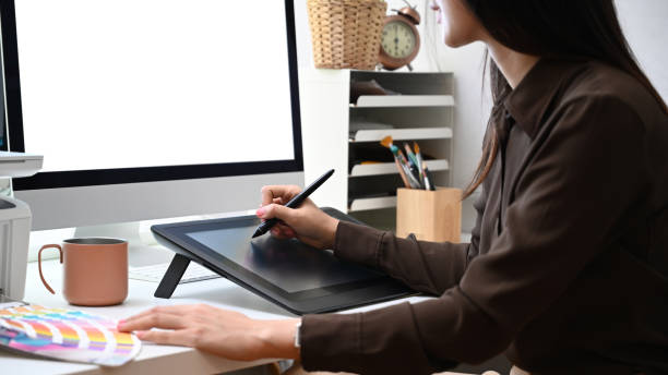 istock Side view of creative woman graphic designer working with graphic tablet and computer at office. 1311766886