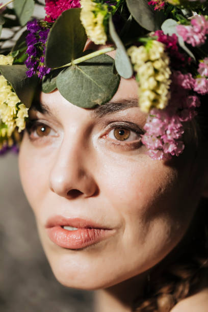 studio-porträts einer frau in ihren dreißiger jahren tragen natürliche blumen im kopf - single flower flash stock-fotos und bilder