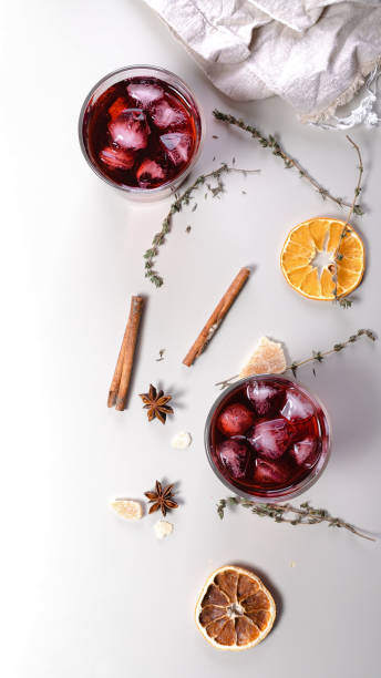 istock Cherry wine cold cocktail. Alcoholic beverage banner format. Dry oranges, cinnamon sticks, oregano, anise and dried ginger. Light background. Vertical shot 1311773279