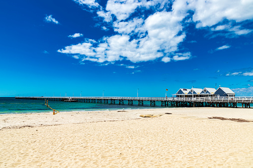 A view of Busselton Jetty in Perth with long jetty, blue skies with white clouds and sandy beach