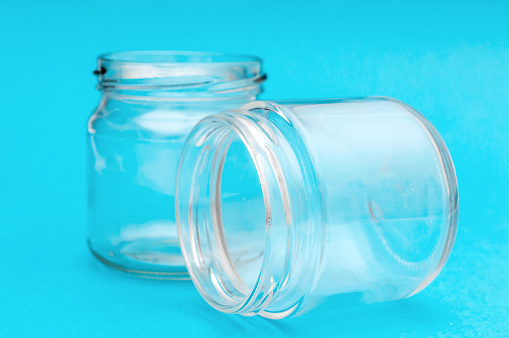 Two empty glass jars on blue background.