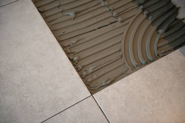 Tiler laying the ceramic tile on the floor. Professional worker makes renovation. Construction. Hands of the tiler. Home renovation and building new house stock photo