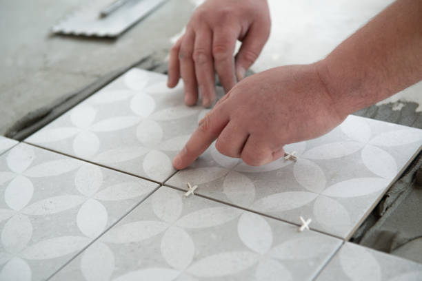 istock Tiler laying the ceramic tile on the floor. Professional worker makes renovation. Construction. Hands of the tiler. Home renovation and building new house 1311784354
