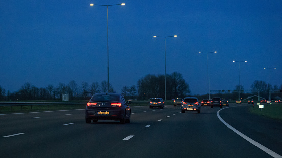 Woerden, province Utrecht, Netherlands, march 27th 2021, blue 2017 Opel Insignia Grand Sport 2.0 CDTi  and other traffic driving on the dutch highway A12 near Woerden at dusk - the A12 motorway is 137 kilometers long and connects the city of The Hague (east) with the German border (east)