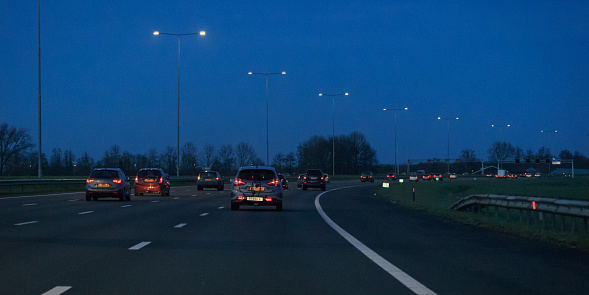 Woerden, province Utrecht, Netherlands, march 27th 2021, gray 2017 Nissan Pulsar MPV (with an empty bicycle rack attached on the towing hook) and other traffic driving on the dutch highway A12 near Woerden at dusk - the A12 motorway is 137 kilometers long and connects the city of The Hague (east) with the German border (east)