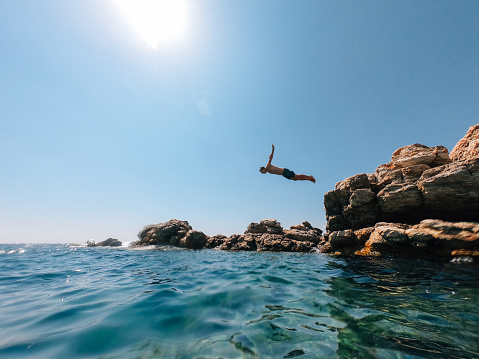 Man diving into the sea from a rock. Italy - Mediterranean sea during summer.