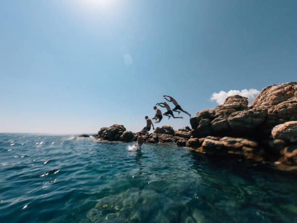 Millennial man is diving from a rock in the sea - Multiple images effect