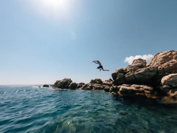 istock Millennial man is diving from a rock in the sea 1311788621