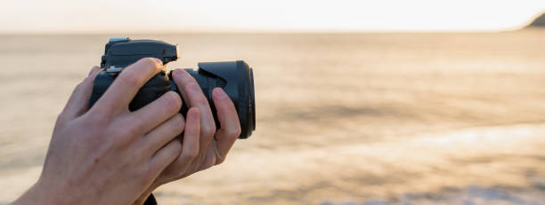 istock Horizontal banner Side view unrecognizable photographer holding reflex camera taking a photo in natural landscape. 1311789512