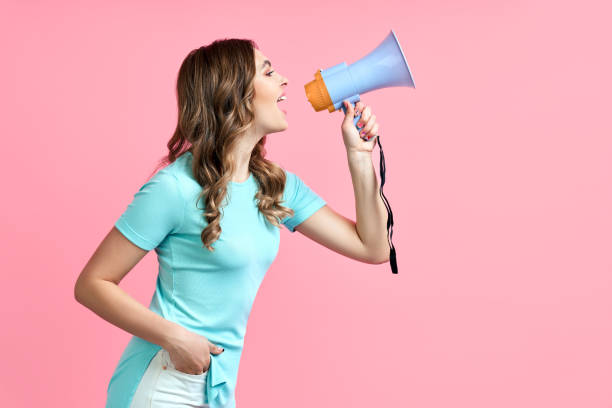 hübsche junge frau schreit in megafon auf rosa hintergrund - megaphone women at attention using voice stock-fotos und bilder