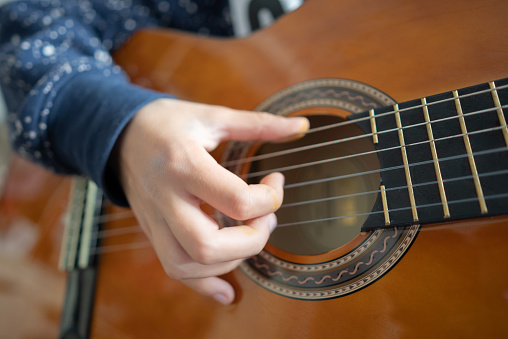 Closeup, hands of man and guitar for music, live talent and creative skill of sound production in home studio. Musician, singer or artist playing notes on acoustic instrument in solo jazz performance