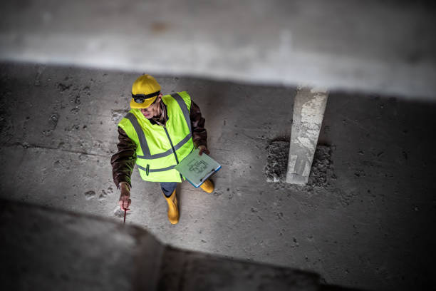 porträt von ingenieur-leseplänen auf der baustelle. ein bauingenieur mit einem schutzhelm, der eine sicherheitsweste trägt, verwendet ein digitales tablet. arbeiten an gebäudeanpassungen und investitionsbewertungen. - business ceo building activity business person stock-fotos und bilder