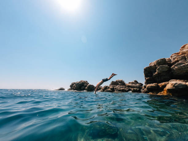 istock Millennial man is diving from a rock in the sea 1311804767