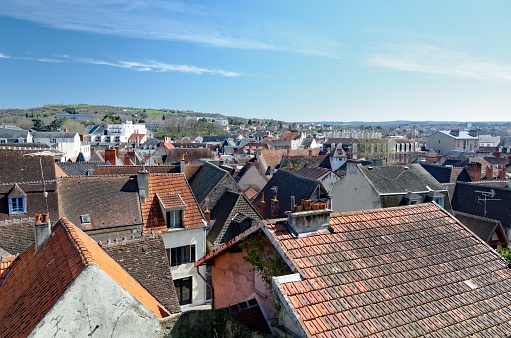 A view of the town of Montluçon in France, with red tiled roof houses, under a blue sky.