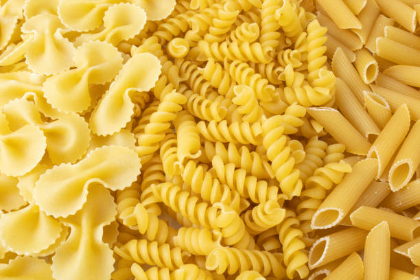 istock Texture with raw fusilli, farfalle and penne pasta. 1311810513
