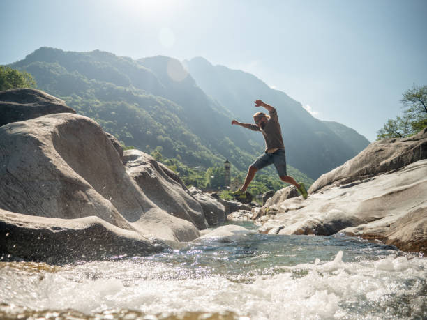 若い男は川の上にジャンプします - ticino canton ストックフォトと画像