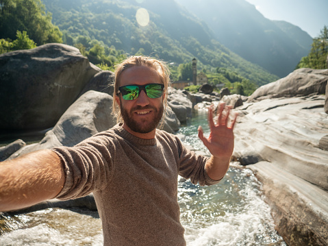 Male having fun outdoors sharing online his adventures with a selfie. Ticino canton, Switzerland