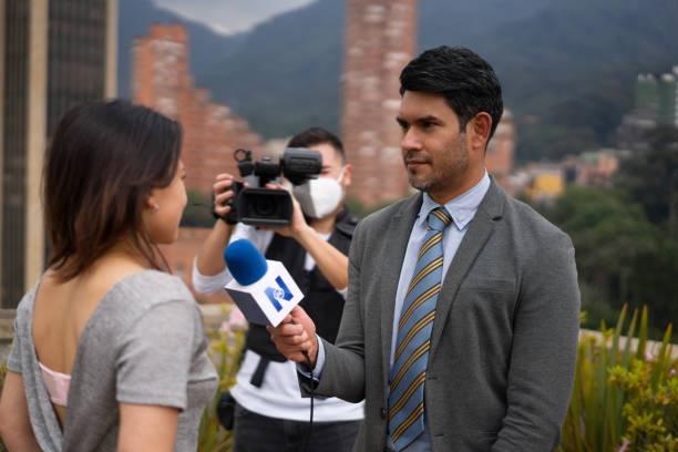 istock Journalist outdoors interviewing a woman in front of the camera 1311819081