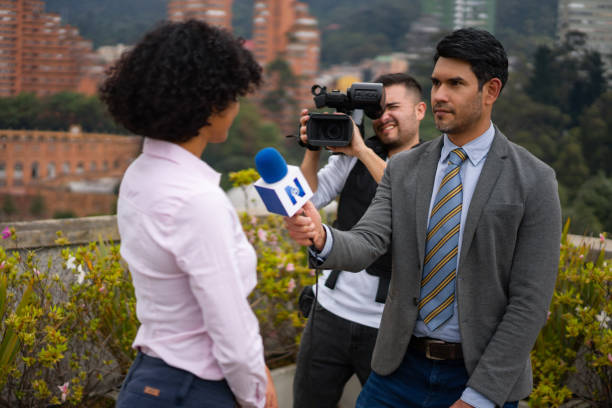 repórter de tv ao ar livre entrevistando uma mulher na frente da câmera - videographer television camera journalist historic world event - fotografias e filmes do acervo