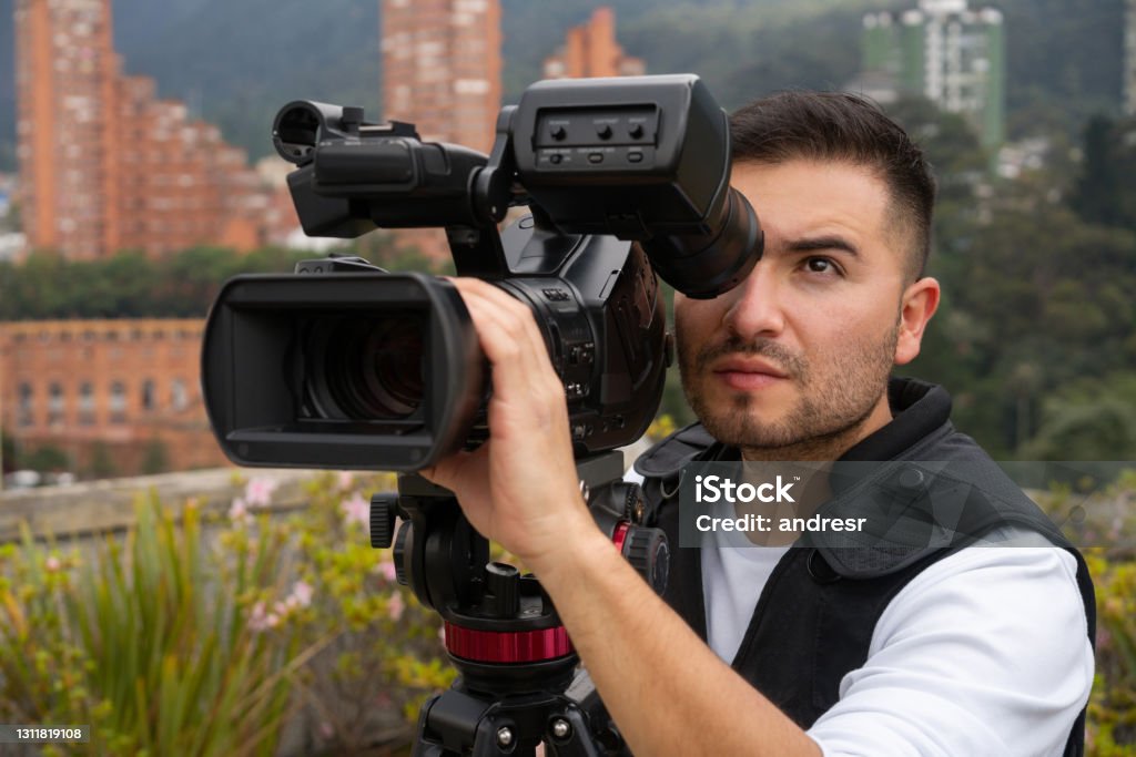 Cameraman outdoors recording breaking news Portrait of a Latin American cameraman outdoors recording breaking news - The Media concepts Camera Operator Stock Photo