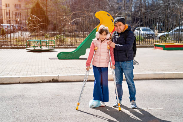 istock dad helps daughter learn to walk on crutches. plaster on your feet. 1311822065