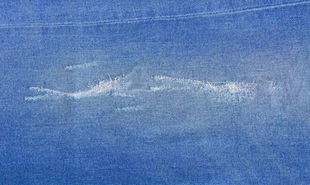 istock Tear of denim texture with a hole and threads showing. 1311822376