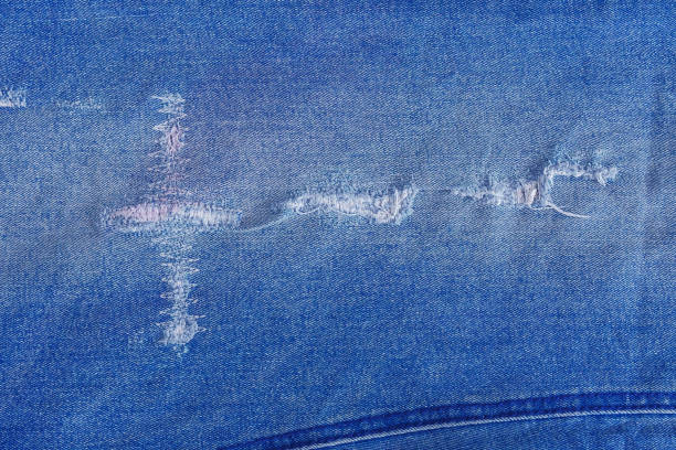 istock Tear of denim texture with a hole and threads showing. 1311822385