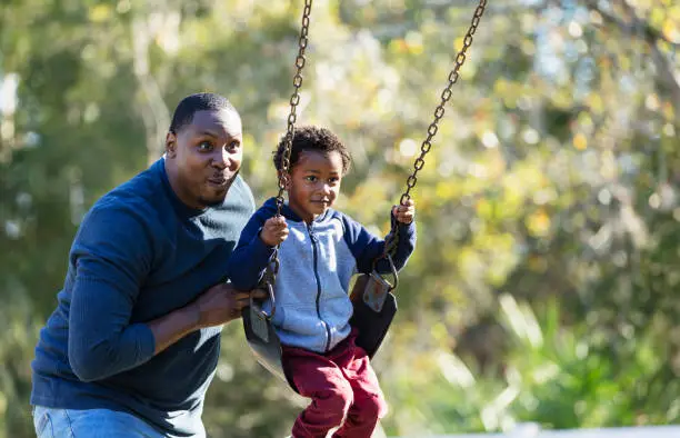 Photo of Boy with father, on playground swing