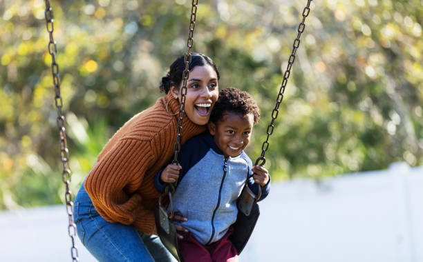 chłopiec z matką, na placu zabaw huśtawka - child swinging playground african descent zdjęcia i obrazy z banku zdjęć