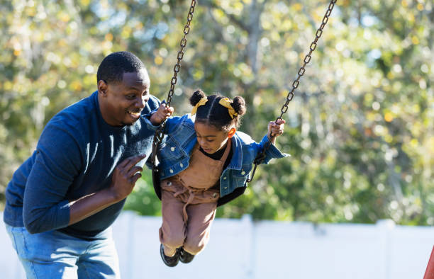 istock Father with daughter on playground swing 1311824546