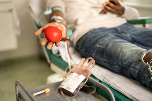 donor die de hart-vormige bal tijdens bloeddonatie knijpt - bloedbank stockfoto's en -beelden
