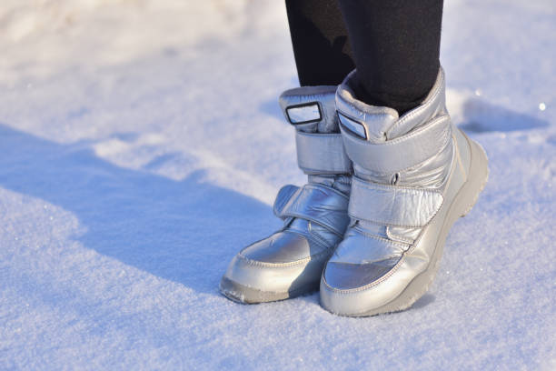 botas de invierno para niños en color plata en la nieve - bota de la nieve fotografías e imágenes de stock
