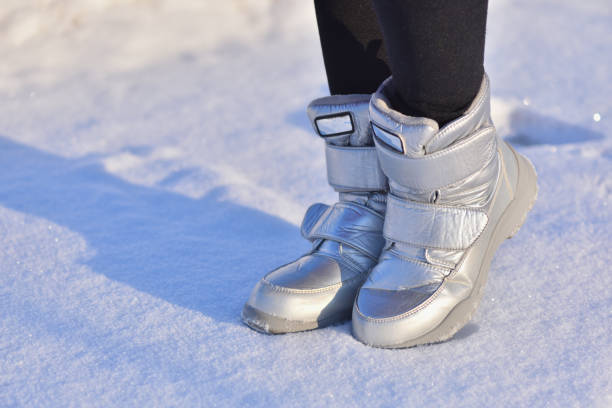 bottes d’hiver d’enfants dans la couleur argentée sur la neige - apres ski photos photos et images de collection