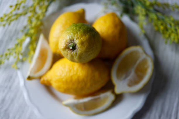 Istanbul, Turkey-March 20, 2021: Lemons and lemon slices on a white plate on a white tablecloth. Still life, Full Frame, Sunlight. Shot with Canon EOS R5.