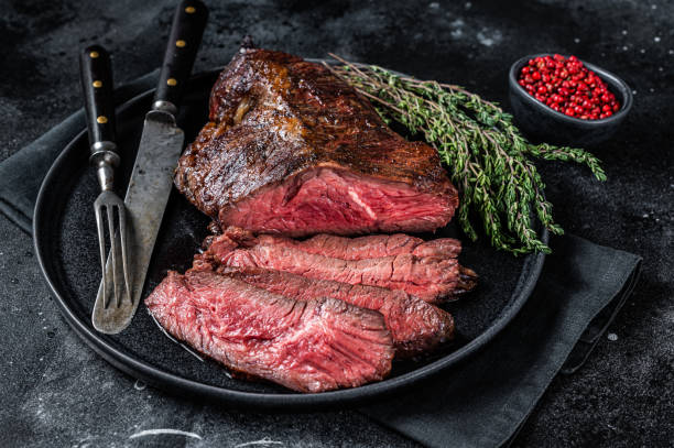 Grilled hanger or Onglet beef meat steak on a plate with thyme. Black background. Top View Grilled hanger or Onglet beef meat steak on a plate with thyme. Black background. Top View. flank steak stock pictures, royalty-free photos & images