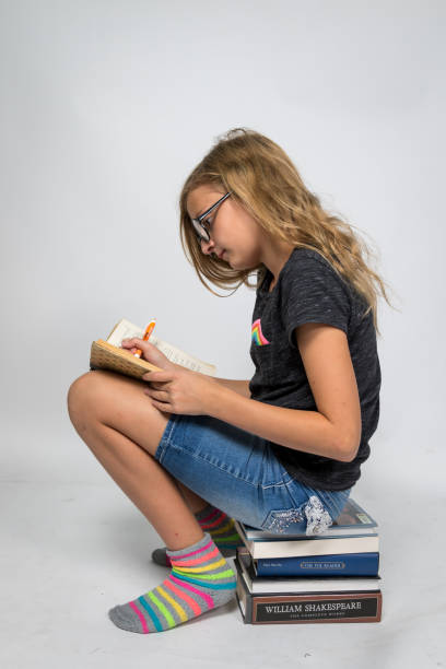 istock Girl Sitting on Books and Writing in Notebook 1311829288