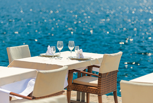 Empty street cafe at sea in Perast, Montenegro. Table and chairs by water. Relax and travel in Balcans, Europe.