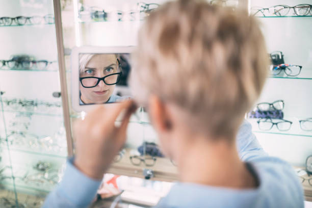 istock A young woman looking at her new glasses in  opticians 1311834830