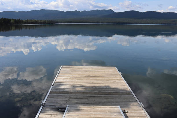 istock Clouds reflecting in a clear bue mountain lake with a dock 1311836519