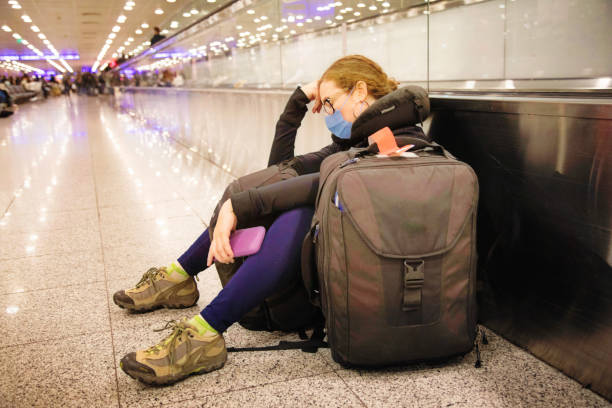 Young Female traveller napping as she waits forever at the airport terminal Young Female traveller napping as she waits forever at the airport terminal, wearing a protective mask. She is travelling during covid-19 times. cancelled stock pictures, royalty-free photos & images