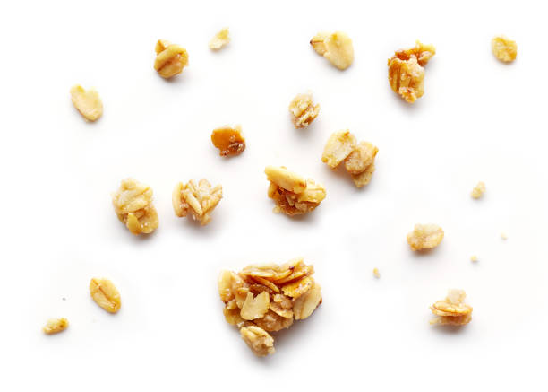 piece and crumbs of homemade granola baked oat meals with butter and sugar crumbs isolated on white background, top view granola stock pictures, royalty-free photos & images